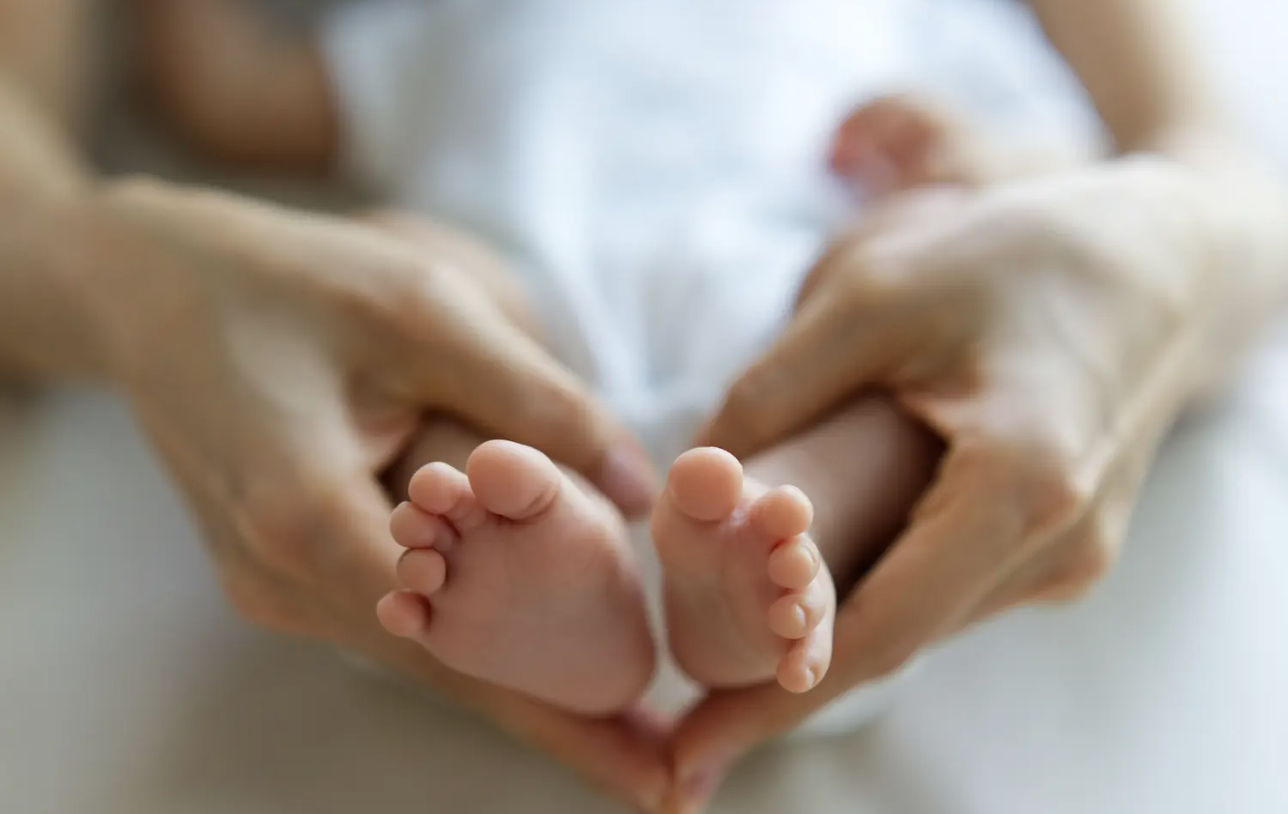 tiny-newborn-baby-s-feet-on-female-heart-shaped